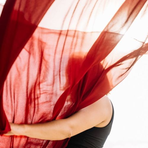 Silhouette of a person in a fluid motion yoga pose against a soft background.